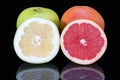 Citrus fruits of red and green grapefruit whole and half isolated on black background close up