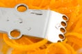 Stainless steel citrus grater on thin curls of orange