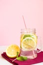 Citrus lemonade water with sliced lemon and mint, healthy and detox water drink in summer on wooden table with pastel pink Royalty Free Stock Photo