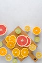 Citrus lobule composition on chopping board. Many halved lemons, limes, grapefruits. Vertical