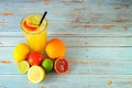 Citrus mix in a tall glass with ice, next to lime, lemon, orange and grapefruit on a wooden table Royalty Free Stock Photo