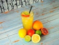 Citrus mix in a tall glass with ice, next to lime, lemon, orange and grapefruit on a wooden table Royalty Free Stock Photo