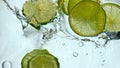 Citrus pieces floating water in super slow motion close up. Lime dropped liquid. Royalty Free Stock Photo