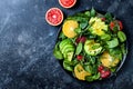 Citrus salad with mixed greens and blood orange on black ceramic plate. Vegan, vegetarian, clean eating, dieting