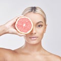 A citrus view. Studio shot of a beautiful young woman holding a grapefruit in front of her eye against a grey background Royalty Free Stock Photo