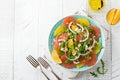 Citrus vitamin salad. Orange, grapefruit, ricotta cheese, pine nuts, red onions and rucola with olive oil in a ceramic plate on a