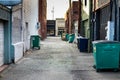 City alley with trash, dumpsters, and garbage cans