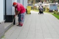 A city cleaner collects garbage near a building near the sidewalk.