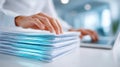 City clerk using AI document summarization technology while reviewing a stack of papers on a desk with a laptop in a Royalty Free Stock Photo