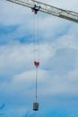 City crane carrying porta potty or portable bathroom with ropes and metal wires on construction equipment in neighborhood