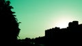 City cyan sky at sunset with strong dark shadows on trees and buildings