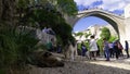 City dog sleeps in the shade under the Old Mostar bridge. Tourists below and on the Stari most Mostar, Bosnia and Herzegovina