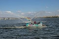 City dwellers on a pleasure boat admire the fountain with a beautiful rainbow. Blue sky background Royalty Free Stock Photo