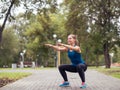 City fitness. Caucasian girl doing squats in the urban park, selected focus Royalty Free Stock Photo