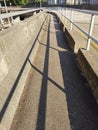 City footpath with shadow of hand rails on busy concrete road side in Hong Kong