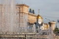 City fountain with splashes and jets of water against the background of buildings and a golden-colored church dome with a cross Royalty Free Stock Photo