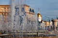 City fountain with splashes and jets of water against the background of buildings and a golden-colored church dome with a cross Royalty Free Stock Photo