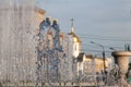 City fountain with splashes and jets of water against the background of buildings and a golden-colored church dome with a cross Royalty Free Stock Photo