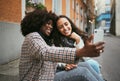 City, friends and women take selfie with phone and sitting on sidewalk laughing and happy together. Photo, video call Royalty Free Stock Photo