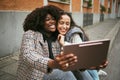 City, friends and women take selfie on tablet while sitting on sidewalk laughing and happy together. Photo, video call