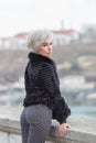 City in fur coat stands leaning on retaining wall and looks over shoulder Royalty Free Stock Photo