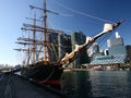 Moored historic sailing ship with iconic cityscape of modern skyscrapers on harbor waterfront, Darling Harbour, Sydney, Australia