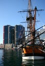 Moored historic sailing ship with iconic cityscape of modern skyscrapers on harbor waterfront, Darling Harbour, Sydney, Australia