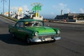 Havana, Cuba - August 26 2018: A green classic car is driving on the first street in Old Havana. Royalty Free Stock Photo