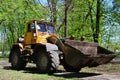 The city improvement team removes the fallen leaves in the park with an excavator and a truck. Regular seasonal work on improving