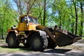 The city improvement team removes the fallen leaves in the park with an excavator and a truck. Regular seasonal work on improving