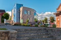 A city landscape with cars parked near a building with interesting architecture. To a square and round window and a