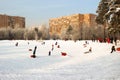 City landscape with children`s winter fun. Children ride down the snowy slide on a tubings or toboggans. Winter outdoor recreatio