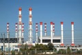 Power station building with many high red and white industrial pipes over clear cloudless blue sky on sunny day front view Royalty Free Stock Photo