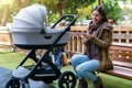 City mother with her newborn baby in the park looking at her mobile phone Royalty Free Stock Photo