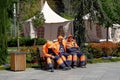 City municipal workers are sitting on a bench for short break after cleaning the city street in april sunny day