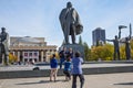 Tourists from China taking pictures at the background of the sculpture of Lenin and the Novosibirsk state academic Opera and ball