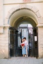 City outdoor portrait of happy young couple in love, posing near pod building with beautiful vintage gate. Pretty girl Royalty Free Stock Photo