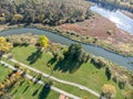 City park with bushy autumnal trees, green lawns, bikeway and river