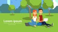 City park couple sitting green lawn using laptop man woman trees cityscape template background copy space horizontal