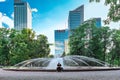 City park with a fountain and a young man resting against the backdrop of skyscrapers in the summer. Urban landscape during the Royalty Free Stock Photo