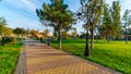 City park, green lawns and trees, random people walking along the paths, urban architecture Royalty Free Stock Photo