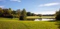 City park in Munich, Germany. Grass field, trees and a pond in the afternoon Royalty Free Stock Photo