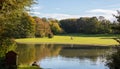 City park in Munich, Germany. Grass field, trees and a pond in the afternoon Royalty Free Stock Photo