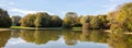 City park in Munich, Germany. Grass field, trees and reflections in a pond Royalty Free Stock Photo