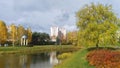 In the city park, a rotunda of concrete columns with a metal roof in the form of a dome, surrounded by shrubbery, neighbors a wate