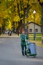 City park worker in a green suit with a garbage bin.