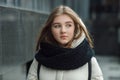 City portrait of young beautiful blonde stylish girl posing in spring fall outdoors in white coat black knitted scarf. Vintage fil Royalty Free Stock Photo