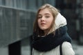 City portrait of young beautiful blonde stylish girl posing in spring fall outdoors in white coat black knitted scarf. Vintage fil Royalty Free Stock Photo