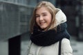 City portrait of young beautiful blonde stylish girl posing in spring fall outdoors in white coat black knitted scarf. Vintage fil Royalty Free Stock Photo