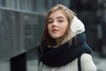 City portrait of young beautiful blonde stylish girl posing in spring fall outdoors in white coat black knitted scarf. Vintage fil Royalty Free Stock Photo